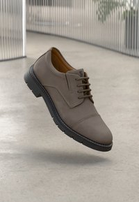 Braune Schnürschuhe aus Leder mit glatter Oberfläche, gestaltet mit einer runden Spitze und strukturierten Akzenten, versehen mit einer kontrastierenden schwarzen Sohle.