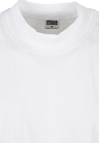 T-shirt in cotone bianco con collo alto. Presenta un'etichetta con la scritta "URBAN CLASSICS" e la taglia "M". Texture liscia, design semplice e senza motivi.
