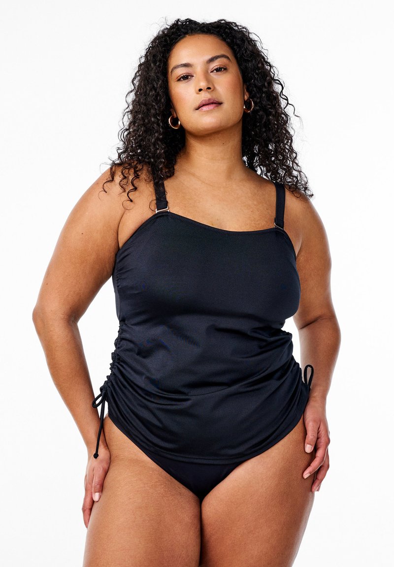 Zwarte badpak met verstelbare bandjes, gerimpelde zijkanten en een strak, gladde textuur. Het ontwerp bevat een bijpassende bikini onderkant.