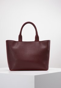 Tmavě červená syntetická taška přes rameno se dvěma krátkými rukojetěmi, strukturovaným tvarem, hladkou texturou a kontrastními červenými akcenty na okrajích.