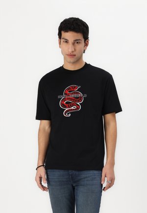 T-shirt di cotone nera con una grafica di serpente rossa e bianca con la scritta "KARL LAGERFELD." Maniche corte, scollo a girocollo e vestibilità rilassata.