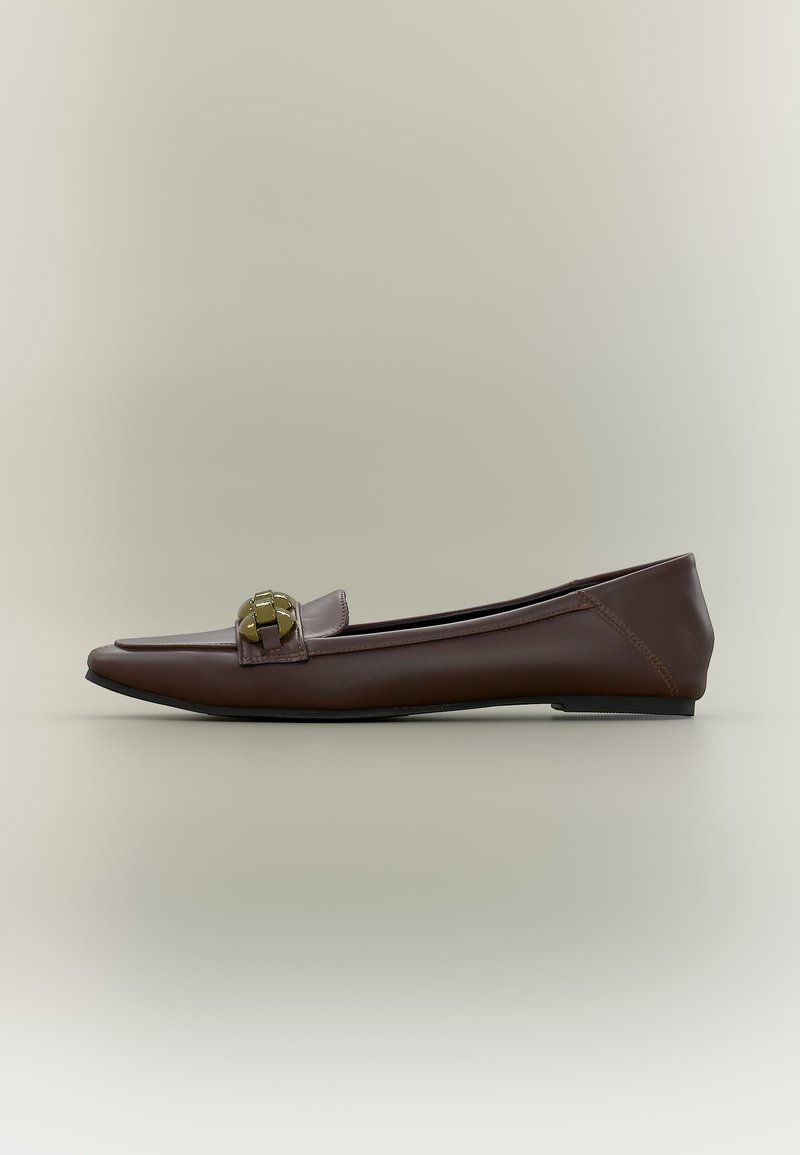 Mocassin plat en cuir marron avec bout carré et détail chaîne dorée sur le dessus, présenté sur un fond neutre.
