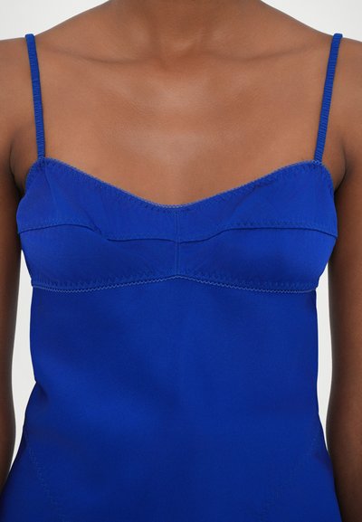 Camisola blu royal con spalline sottili, caratterizzata da un design a pannelli cuciti e una texture liscia. La parte superiore ha un leggero scollo a barchetta.
