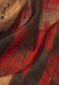 Foulard in seta con pennellate astratte rosse e nere su sfondo beige, dalla texture morbida e dal design fluttuante.