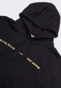 Felpa nera con cappuccio caratterizzata da testo dorato: "MANY HEADS IUTER ONE GROUP." Tessuto morbido con cappuccio regolabile e polsini a costine.