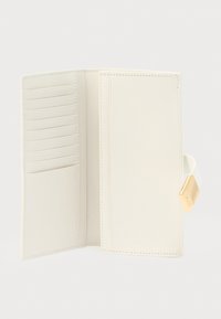 Cartera blanca de cuero con múltiples ranuras para tarjetas y bolsillo lateral. Cuenta con un broche dorado como detalle. Textura suave y diseño minimalista.