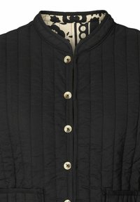 Giacca nera imbottita con colletto alto, chiusura frontale a bottoni metallici e foderatura stampata. Include una tasca sul petto.
