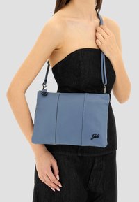 Borsa a spalla in pelle blu con finitura texturizzata, caratterizzata da una forma rettangolare semplice e un accento con logo sul davanti. Fibbia per la regolazione della tracolla inclusa.