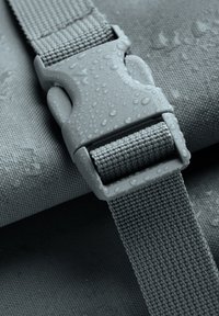 Sangle en tissu imperméable gris avec une boucle en plastique affichant des gouttes d'eau. Présente un motif de tissage texturé, mettant en avant la durabilité et la fonctionnalité.