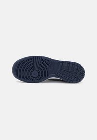 Tamsiai mėlyni sportbačių pado su tekstūruotu guma, kuriame matomi apskrito ir horizontalaus raštai. Nike logotipas matomas vidurinėje dalyje.