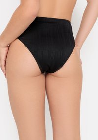 Bas de bikini noir taille haute avec un tissu texturé et des bords sans couture, présentant de subtiles rayures verticales et un design à couverture intégrale à l'arrière.
