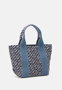 Granatowa torba na ramię z jasnoniebieskimi uchwytami, z powtarzającym się białym wzorem tekstu "See By Chloe" na tkaninie.