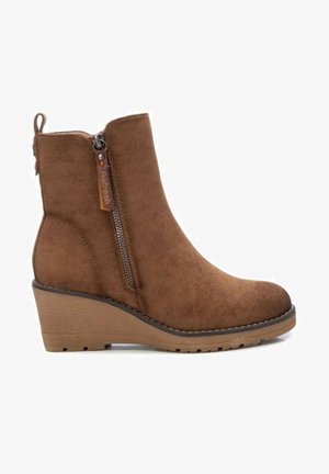 Botte cheville en daim marron avec fermeture éclair latérale, talon compensé et languette à l'arrière, conçue pour un usage décontracté.