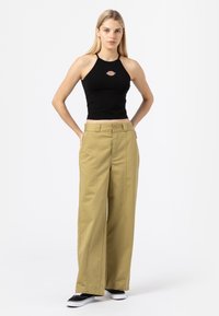 Svart kort halterneck-top med logotyp, kombinerad med vida khakibyxor med framfickor och knappstängning, bärs med svarta sneakers.