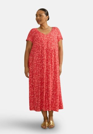 Rød blomster maxi-kjole med V-hals, korte ærmer og løs pasform. Har en samlet talje og en svævende silhuet. Bæres med gyldne sandaler.