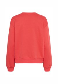 Sweatshirt corail avec un col crew, des manches longues, des poignets et un ourlet côtelés. Texture lisse avec une coupe relaxée et sans motifs visibles.