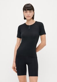 Zwart sporttop met korte mouwen, gladde textuur, getailleerd ontwerp, vlakke naaddetails, gecombineerd met zwarte fietsbroek voor een gecoördineerde look.