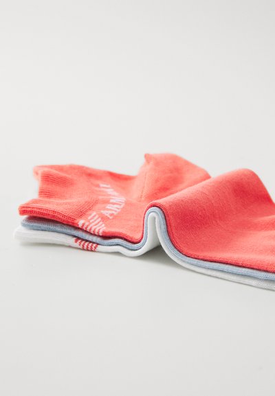 Chaussettes en coton de couleur corail, blanche et bleu clair, présentant une texture côtelée et des rayures audacieuses. Comprend le lettrage de la marque sur la chaussette corail.