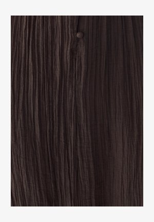 Tekstuirana smeđa tkanina s vertikalnim naborima i malim odgovarajućim gumbom, koja prenosi meki, naborani izgled.