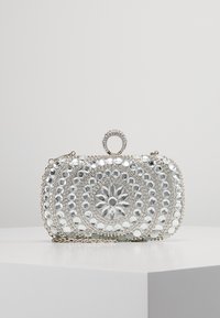 Pochette argentée avec des motifs circulaires complexes en perles, ornée de strass translucides, dotée d'une poignée supérieure et d'une chaîne en métal.