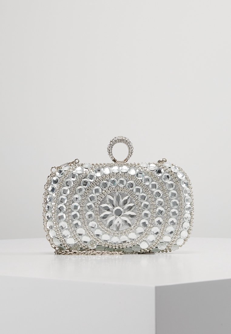 Pochette argentée avec des motifs circulaires complexes en perles, ornée de strass translucides, dotée d'une poignée supérieure et d'une chaîne en métal.