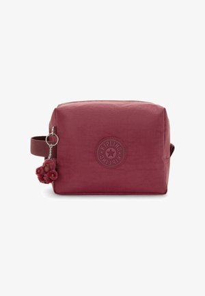 Red textured zippered toiletry bag with a round logo, adjustable handle, and pom-pom keychain attached. Rectangular design.