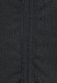 Primo piano di un tessuto a coste nero con una trama a maglia verticale e linee di cucitura sottili.