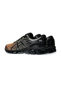 Baskets de sport noires et orange avec une tige en mesh texturé, des rayures noires prononcées, une semelle rembourrée et des accents de technologie GEL.