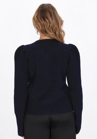 Maglione lavorato a maglia blu navy con maniche a sbuffo e vita aderente. Tessuto morbido con orlo a coste e scollo rotondo.