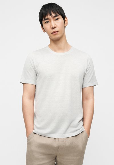 Ανοιχτό γκρι βαμβακερό t-shirt με κοντά μανίκια και στρογγυλή λαιμόκοψη, σε συνδυασμό με μπεζ λινό σορτς. Λείο ύφασμα, απλός σχεδιασμός.