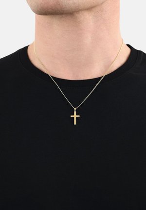 Collana con pendente a croce in oro su una catena sottile, indossata sopra una t-shirt nera. La croce presenta una superficie liscia e un design geometrico semplice.