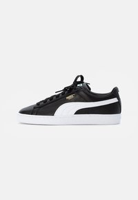 Sneaker in pelle nera con una striscia bianca, parte superiore testurizzata, lacci neri e suola in gomma bianca con marchio in rilievo.