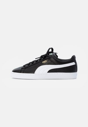 Baskets en cuir noir avec une rayure blanche, tige texturée, lacets noirs et semelle en caoutchouc blanc avec logo en relief.
