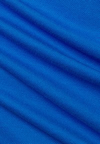 Heldere blauwe stof met een gestructureerd, geweven patroon, dat subtiele golven en diepte laat zien en de zachte en duurzame kwaliteiten benadrukt.