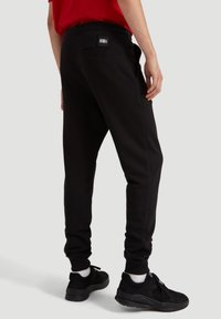 Sorte sweatpants med en tapered fit, elastisk talje og en baglomme. Sammen med sorte sneakers og hvide ankelstrømper.
