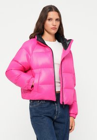 Veste matelassée de couleur rose vif avec un col noir, dotée d'une fermeture éclair, de poignets élastiques et d'une coupe courte. Texture lisse.