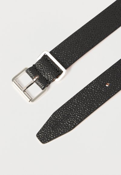 Μαύρη ζώνη από δέρμα με υφή, με ασημένια ορθογώνια αγκράφα και μία τρύπα στην μυτερή άκρη, τοποθετημένη επίπεδα σε λευκό φόντο.