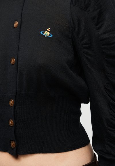 Μαύρο κοντό ζακέτα με καφέ κουμπιά, ριγωτή υφή και φουσκωτά μανίκια με μικρό πολύχρωμο κεντητό σχέδιο.