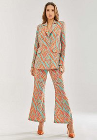 Colorful plaid suit featuring a tailored blazer and flared pants in orange, teal, and pink hues. Material appears smooth with a structured design.