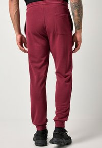 Bordå joggers med elastisk midjeband, avsmalnande ben och en bakficka. Materialet verkar mjukt med en slät yta. Bärs med svarta sneakers.