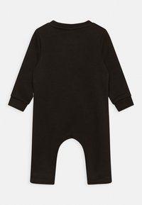 Musta, pitkähihaisten vauvan body pehmeästä kankaasta, jossa on pyöreä pääntie, hihansuut ja takana laskostettu istuinosa.