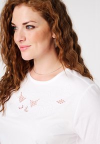 Witte katoenen T-shirt met ingewikkelde witte borduursels en meshdetails bij de halslijn. Ronde kraag en korte mouwen.