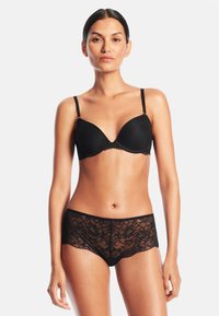 Svart vadderad bh med spetsdetaljer och justerbara axelband, matchad med svarta spetsboxer med blommönster och scalloped kanter.