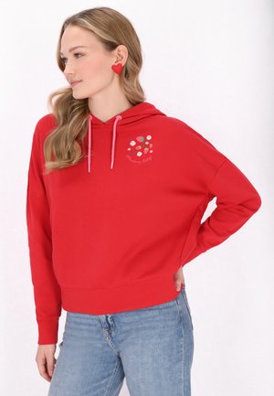 Rode hoodie met roze trekkoorden, heeft bloemenborduursels en tekstdetails. Ontspannen pasvorm met geribbelde manchetten en zoom, gedragen met blauwe jeans.