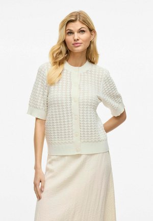 Cardigan ligero de punto en blanco roto con mangas cortas, escote redondo y cierre de botones. Presenta un patrón texturizado y dobladillo acanalado.