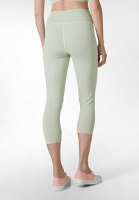 Vaaleanvihreät capri-leggingsit, jotka on valmistettu pehmeästä materiaalista, jossa on ribattu vyötärö. Niissä on sileä pinta ja istuva siluetti.