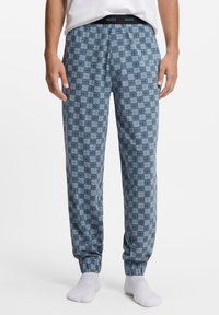 Blauwe pyjamabroek met patroon en elastische tailleband, voorzien van een herhaald logoontwerp. Gemaakt van zachte stof met taps toelopende boorden bij de enkels.
