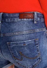 Pantalones cortos de mezclilla en azul claro con un acabado desgastado. Presentan una etiqueta de cuero con la inscripción "LTB" y un bolsillo trasero con un diseño bordado.