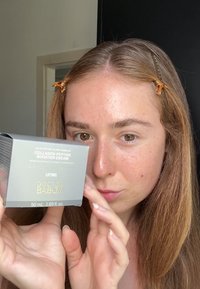 Crème Booster de Peptides de Collagène dans un emballage métallique argenté, avec texte doré, taille de 50 mL. Surface lisse avec une forme carrée.