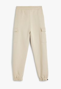 Beige Jogginghose mit elastischem Bund, elastischen Bündchen und zwei Seitentaschen im Cargo-Stil. Weicher Stoff mit glatter Textur.
